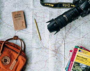 Travelers study a map and weather forecast beside luggage while planning a seasonal trip.