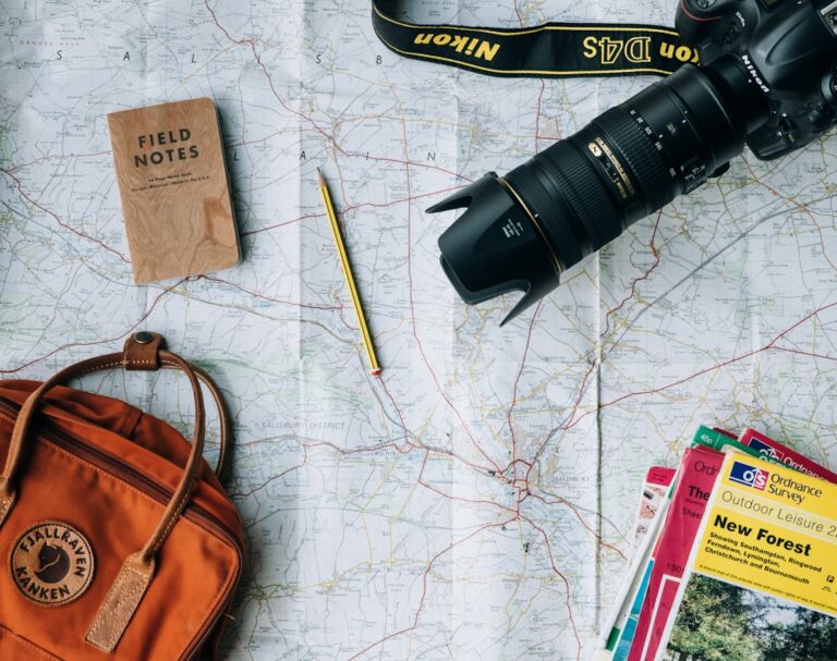Travelers study a map and weather forecast beside luggage while planning a seasonal trip.