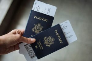 Traveler organizing a passport, visa papers, vaccination card, and printed itinerary on a table.