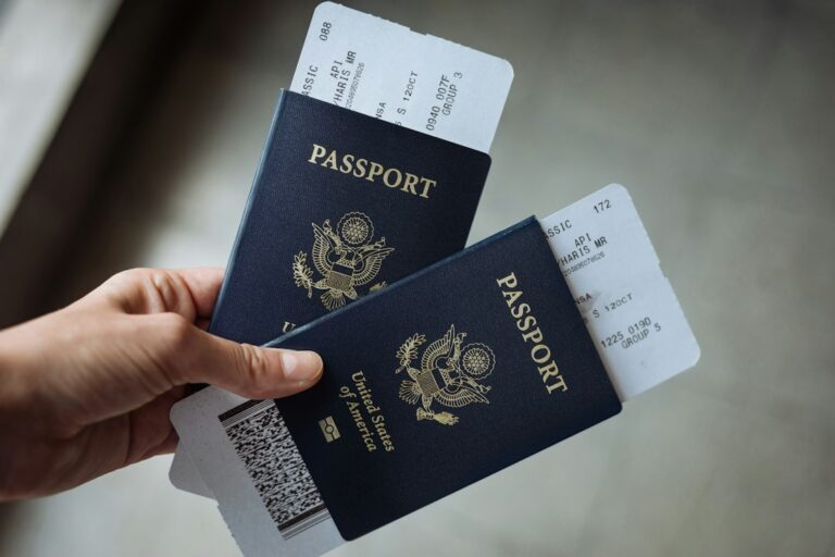 Traveler organizing a passport, visa papers, vaccination card, and printed itinerary on a table.